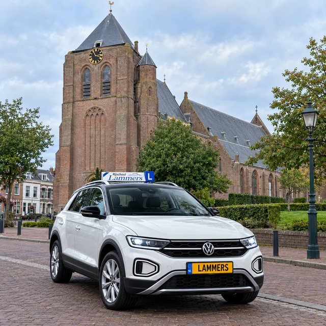 De witte Volkswagen T-Roc van Rijschool Lammers voor de kerk met de grote zwarte klok in Monster